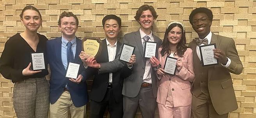 Six CUDL students in suits and blazers holding award plaques after a competition