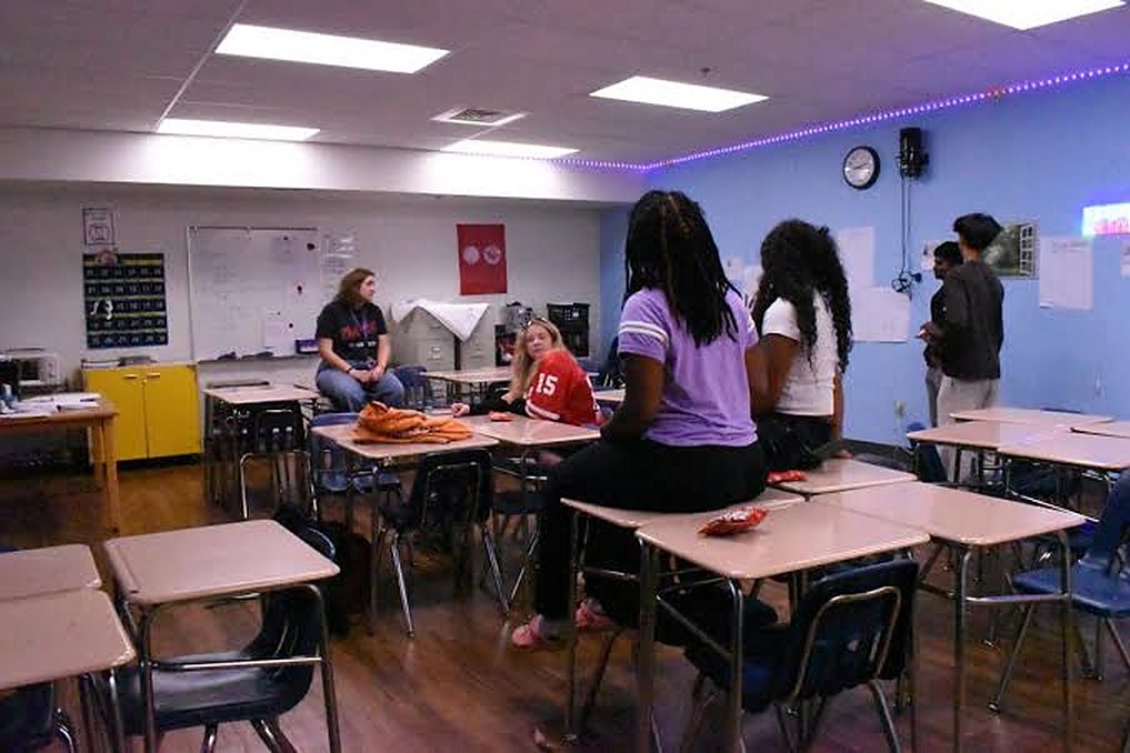 Students talking during a club meeting in a classroom