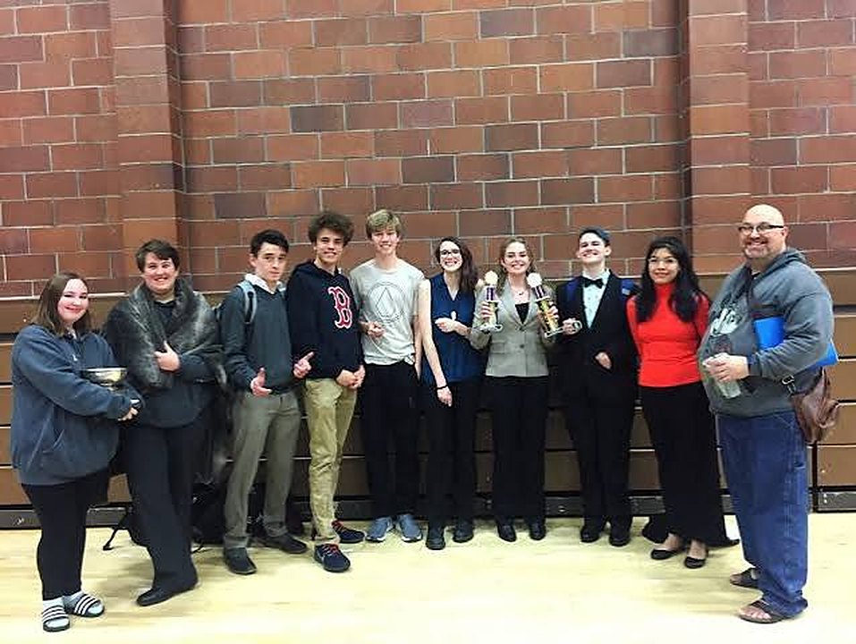 A team and their coach in a school gym with trophies